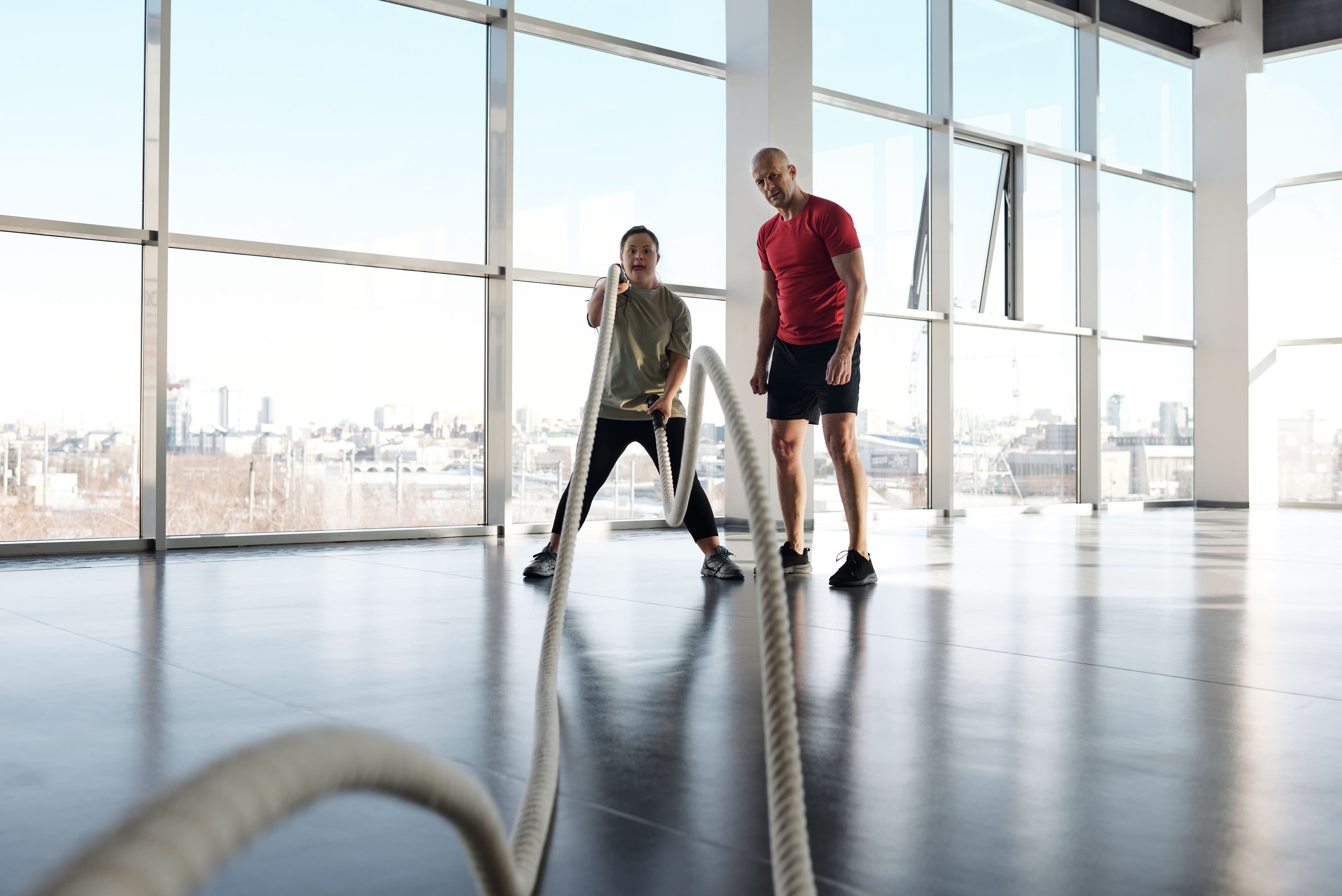 Coach guiding a client through a workout with battle ropes